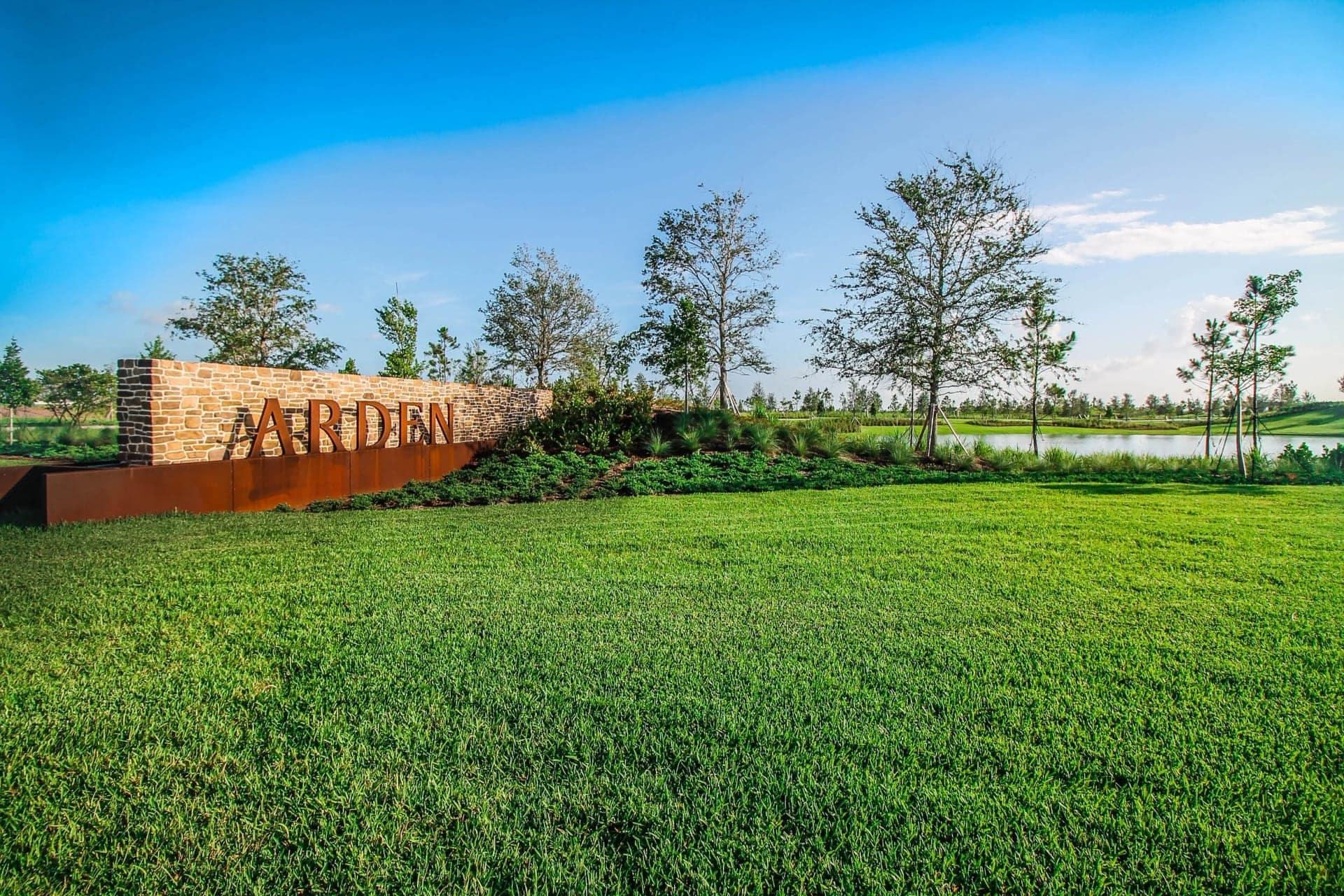 Arden community entrance sign with green lawn, trees, and lake